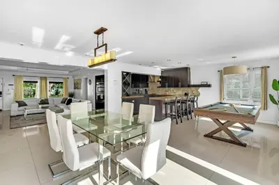 a dining room and kitchen with a glass table and white chairs at Spacious 3 bedroom Home with Oversized Pool & Backyard in Miami
