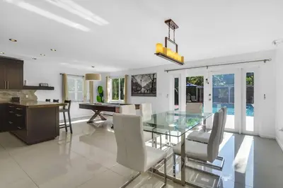 a dining room with a glass table and white chairs at Spacious 3 bedroom Home with Oversized Pool & Backyard in Miami