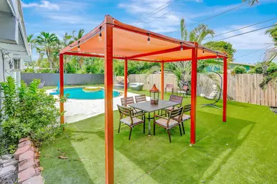 a table and chairs under an orange canopy in a yard at Fort Lauderdale Tropical Oasis Pool Retreat in Fort Lauderdale
