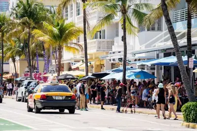 a crowd of people walking down a street with a taxi at Villa Jazmin Beach in Miami Beach