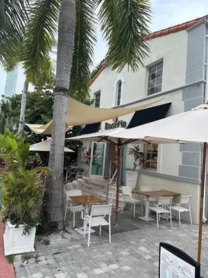 a patio with tables and umbrellas in front of a building at Villa Jazmin Beach in Miami Beach