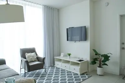 a living room with a couch and a tv on a wall at Luxury apartment in Doral miami, 1 Bd in Miami