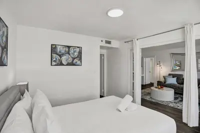 a bedroom with a white bed and a living room at Adorable 2 Bedroom Condo Beach Service 1110 in Miami Beach