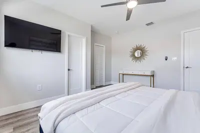 a white bedroom with a large bed and a flat screen tv at Miami Modern Oasis Retreat - Close to Airport in Miami