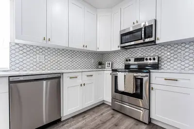a kitchen with white cabinets and stainless steel appliances at Miami Modern Oasis Retreat - Close to Airport in Miami