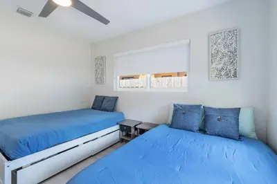 two beds in a white room with blue pillows at Cozy Victoria Park Retreat Unit 3 - Las Olas Beach in Fort Lauderdale