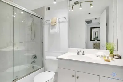 a white bathroom with a sink and a shower at 2BR Pool Ocean View in Miami Beach