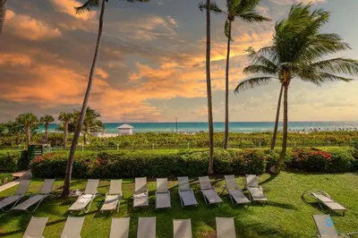 a group of chaise lounges and palm trees at the beach at 2BR Pool Ocean View in Miami Beach