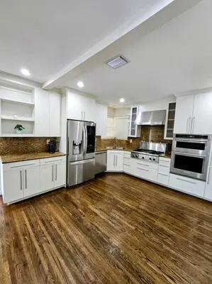 a large kitchen with white cabinets and wooden floors at Brickell Enclave Sunny Retreat with pool in Miami