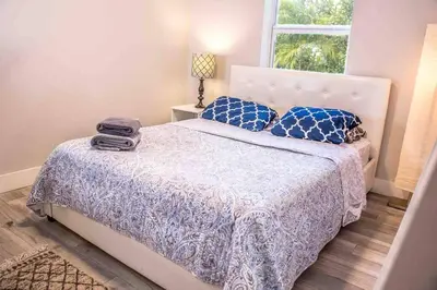 a bedroom with a bed with blue pillows and a window at HOUSE WITH POOL and BBQ, 12 MIN to the BEACH in Miami Shores