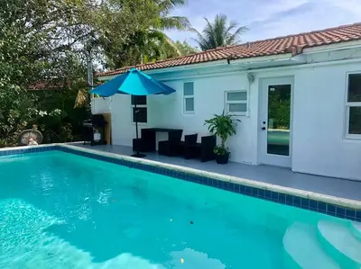 a house with a swimming pool and an umbrella at HOUSE WITH POOL and BBQ, 12 MIN to the BEACH in Miami Shores