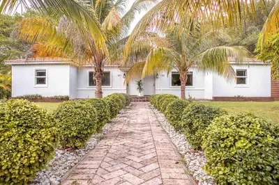 a house with palm trees and a brick walkway at HOUSE WITH POOL and BBQ, 12 MIN to the BEACH in Miami Shores