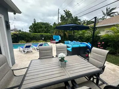 a wooden table with chairs and an umbrella next to a pool at POOLSIDE MANOR - Men Only Clothing-Optional in Fort Lauderdale