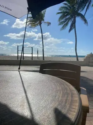 a table with a chair and an umbrella on the beach at Hollywood Townhouse steps to beach and famous Broadwalk in Hollywood Beach