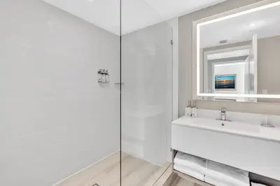 a white bathroom with a sink and a mirror at Grand Deluxe Two Bedroom Suite with Balcony Water Views, Corner in Miami Beach