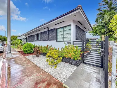 a white house with a fence and some plants at Los Patios Home Suites in Miami Beach