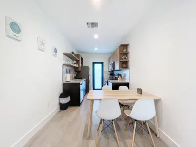 a kitchen with a wooden table and white chairs at Los Patios Home Suites in Miami Beach