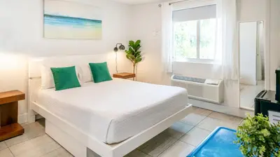 a white bedroom with a white bed with green pillows at 7130 Costa Boutique in Miami Beach
