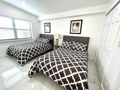 two beds in a bedroom with black and white comforters at Miami Oasis Near Beach in North Miami