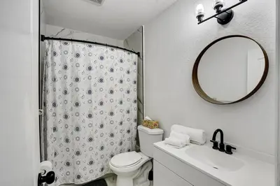 a bathroom with a toilet and a sink and a mirror at 8BR-4BA Spacious House, Sleeps 20, Pool, Fenced Yd in Miami