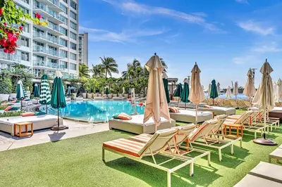 a resort pool with lounge chairs and umbrellas at 1100 West South Beach Lux Waterfront Studio in Miami Beach