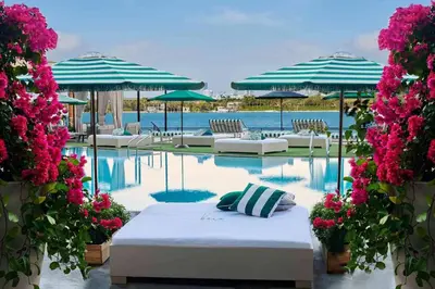 a pool with a bed and chairs and umbrellas at 1100 West South Beach Lux Waterfront Studio in Miami Beach