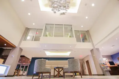 a lobby with two chairs and a table and a chandelier at Holiday Inn Express & Suites Miami Airport East by IHG in Miami