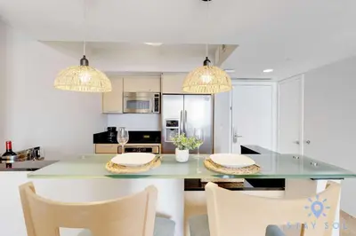 a kitchen with a table with chairs and two chandeliers at 1BR Apartment with beautiful view in Sunny Isles Beach