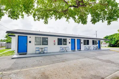 a building with blue doors and tables in a parking lot at Centrally Located Hallandale Beach Condo in Hallandale Beach
