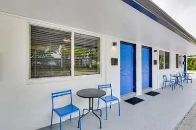 a patio with chairs and a table and blue doors at Centrally Located Hallandale Beach Condo in Hallandale Beach