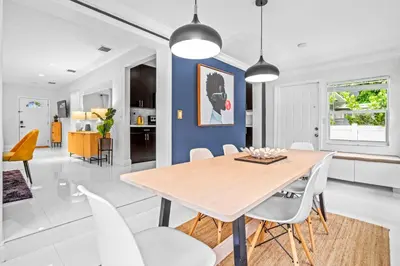 a dining room with a wooden table and white chairs at ArtHaus- Fully Stocked Kitchen and Fenced Yard in Miami