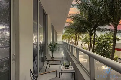 a balcony with chairs and tables and palm trees at 2BR Apartment with Rooftop Pool in Hollywood