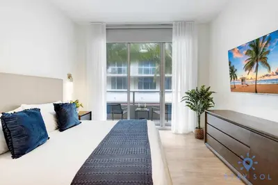 a bedroom with a large white bed with blue pillows at 2BR Apartment with Rooftop Pool in Hollywood