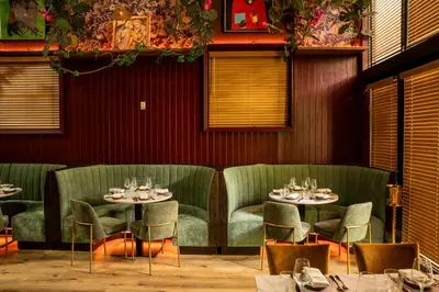 a dining room with two tables and green chairs at The Daydrift in Miami Beach