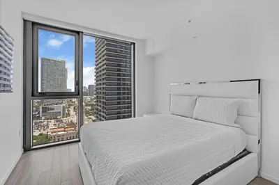a bedroom with a white bed and a large window at Luxury Downtown Miami Apartment in Miami
