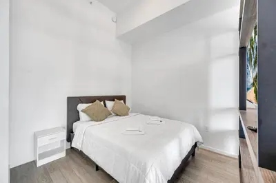 a white bedroom with a bed with white sheets and pillows at Luxury Downtown Miami Apartment in Miami