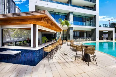 a building with a swimming pool and a patio with tables and chairs at Ultimate Elegance Studio with Panoramic City Views in Miami