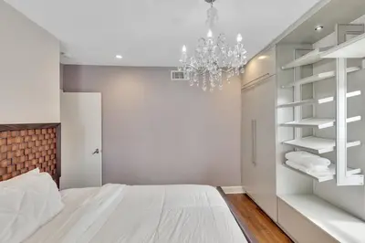 a white bedroom with a bed and a chandelier at Ft Lauderdale Casa de Las Olas in Fort Lauderdale