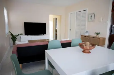 a living room with a tv and a table and chairs at Central Getaway in Little Havana Near Airport, Wynwood, Calle 8 Brickell, Coral Gables and more , Fenced parking in Miami