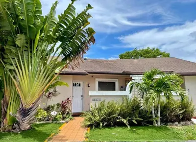 a house with a palm tree in front of it at Beach Lake Paradise - Super Location! in Fort Lauderdale