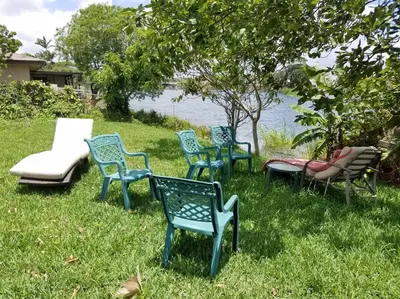 a group of chairs sitting in the grass by the water at Beach Lake Paradise - Super Location! in Fort Lauderdale