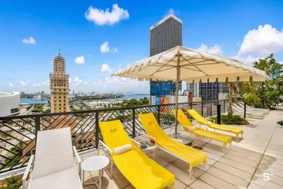 a row of yellow chairs and an umbrella on a balcony at Miami Luxury 27th Floor, Best Waterfront Balcony View & City Lights, Pool,Gym,Spa in Miami