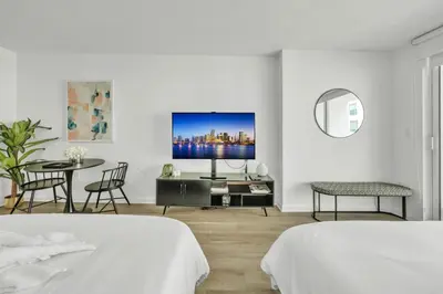 a white room with two beds and a tv on a wall at Marvelous Studio in Brickell Free Parking in Miami