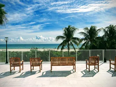 a group of chairs sitting on a patio overlooking the beach at Luxury Ocean Front Condo on Millionaires Row in Miami Beach