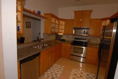 a kitchen with wooden cabinets and stainless steel appliances at Luxury Ocean Front Condo on Millionaires Row in Miami Beach