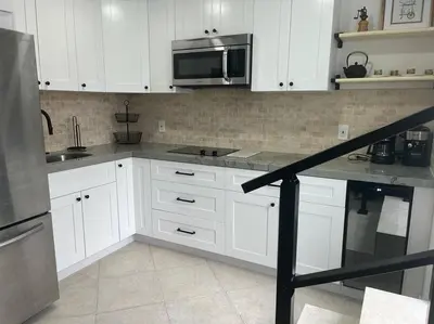 a kitchen with white cabinets and stainless steel appliances at Coastal Haven 5 Min to Beach, Patio, BBQ in Dania Beach