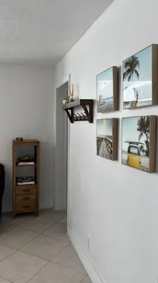 a room with a white wall with pictures on it at Coastal Haven 5 Min to Beach, Patio, BBQ in Dania Beach
