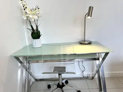 a glass desk with a lamp and a vase of flowers at Doral Studio with Fabulous View in Miami