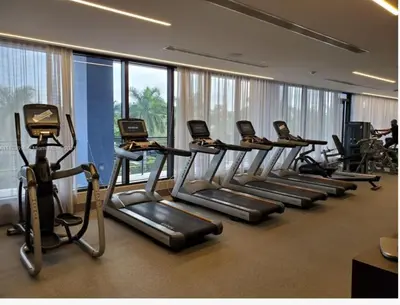 a row of treadmills in a gym with windows at Doral Studio with Fabulous View in Miami