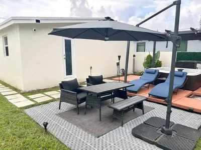 a patio with a table and chairs and an umbrella at Modern Home w Jacuzzi Near Wynwood-Design District-MIA Airport in Miami